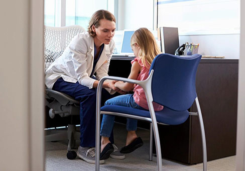 a woman talking to a little girl sitting on a chair